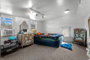 Carpeted bedroom with track lighting, lofted ceiling, and cooling unit