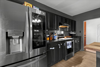 Kitchen featuring dark cabinets, stainless steel fridge with ice dispenser, electric range, and light wood finished floors