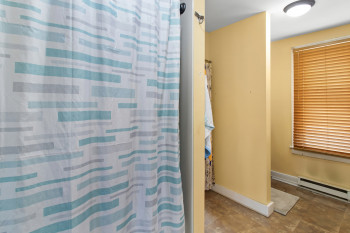 Bathroom featuring curtained shower, a baseboard radiator, and stone finish flooring