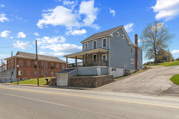 View of front of home with covered porch, a garage, and a chimney