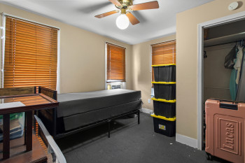 Bedroom with dark carpet, ceiling fan, and a closet