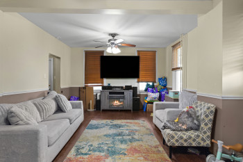 Living area with ceiling fan, dark wood-type flooring, and a fireplace