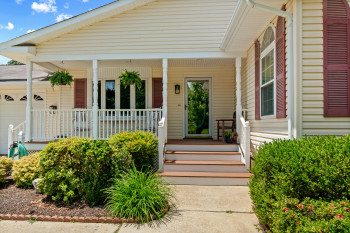 Inviting entrance to yourhome with cream-colored vinyl siding and a covered porch