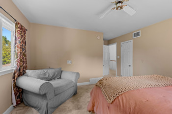 Carpeted room with a ceiling fan, a window with white trim, and a white interior door