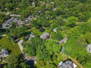 Aerial perspective highlighting the property with extensive tree coverage and surrounding residences