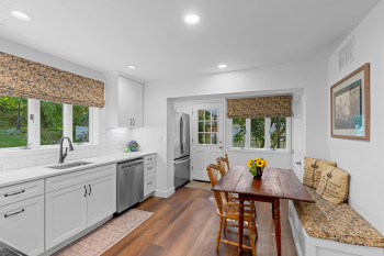 Renovated eat-in kitchen with quartz counters, pantry, coffee bar, banquet seating, and patio access