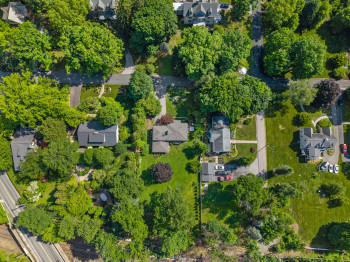 Expansive property featuring mature trees and a substantial green lawn