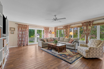 Family room is surrounded by wide, deep windows, accentuating the hardwood flooring.