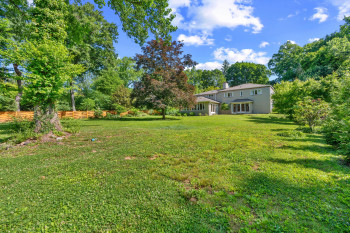 The expansive lawn includes mature trees  and a privacy fence