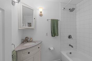 Bathroom featuring a corner vanity with a light-colored countertop and undermount sink, brushed nickel faucet, and a wall-mounted medicine cabinet