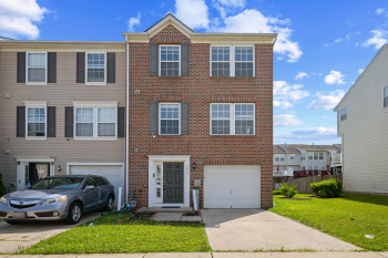 Three-story townhouse featuring a brick front and 1 car garage