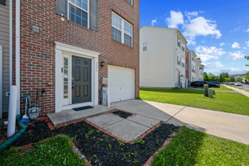 Brick exterior featuring a paneled entry door with sidelight, white trim, and a one-car garage