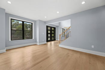Hardwood flooring throughout, recessed lighting, and a modern entry door with multiple glass panes