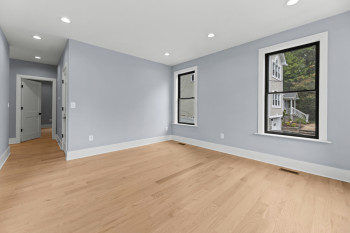 Recessed lighting, light wood-finish flooring, white trim, and two windows with dark frames
