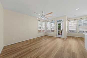 Spacious room with wood-finish flooring, abundant natural light, ceiling fan with integrated lighting, and direct access to an outdoor area