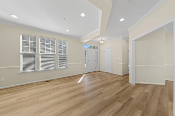 Recessed lighting, wood-finish flooring, multiple windows, crown molding, and wainscoting details enhance this interior space