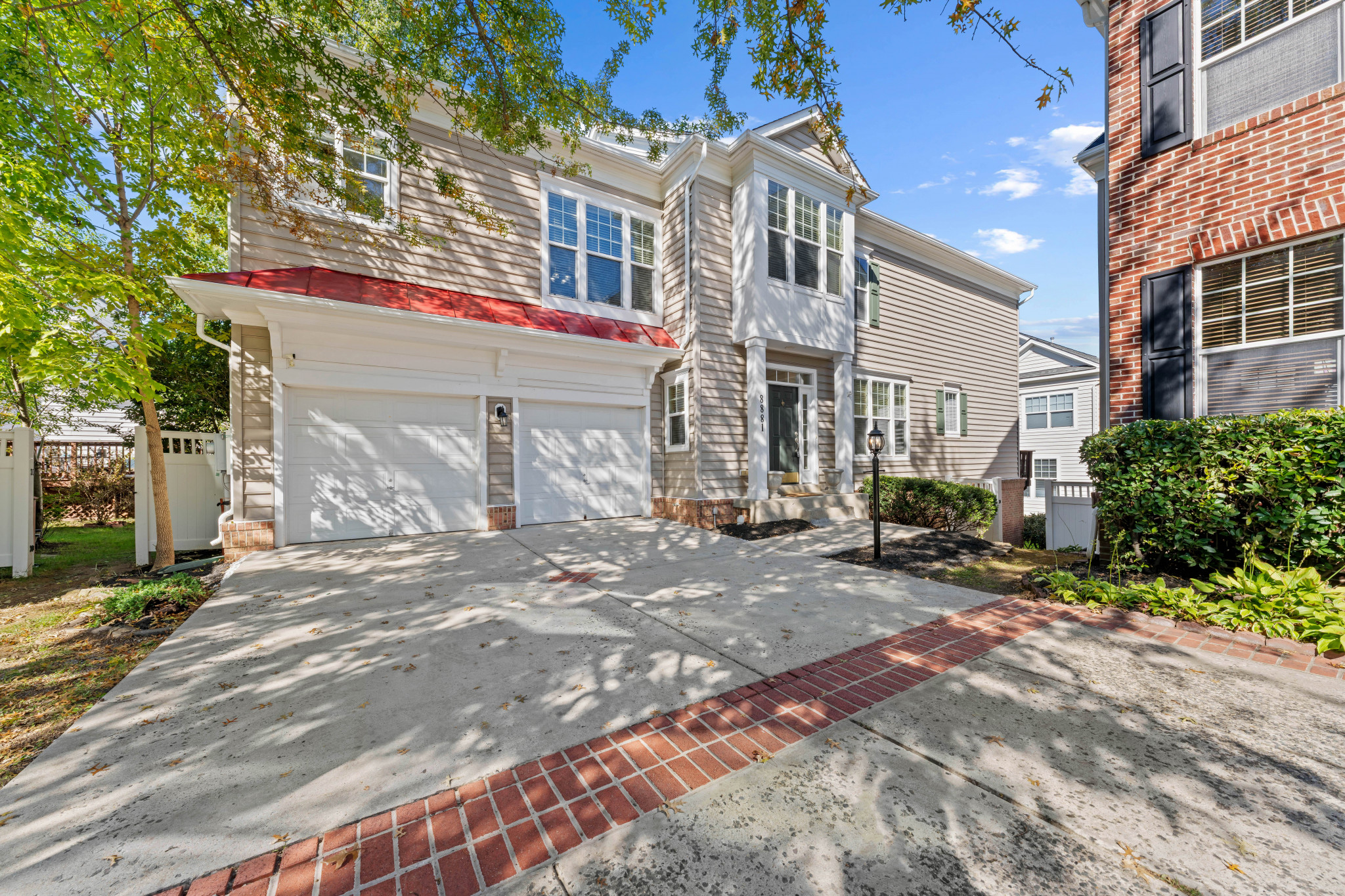 Two-story façade featuring a bay window, a dual garage, and a concrete driveway with brick accents