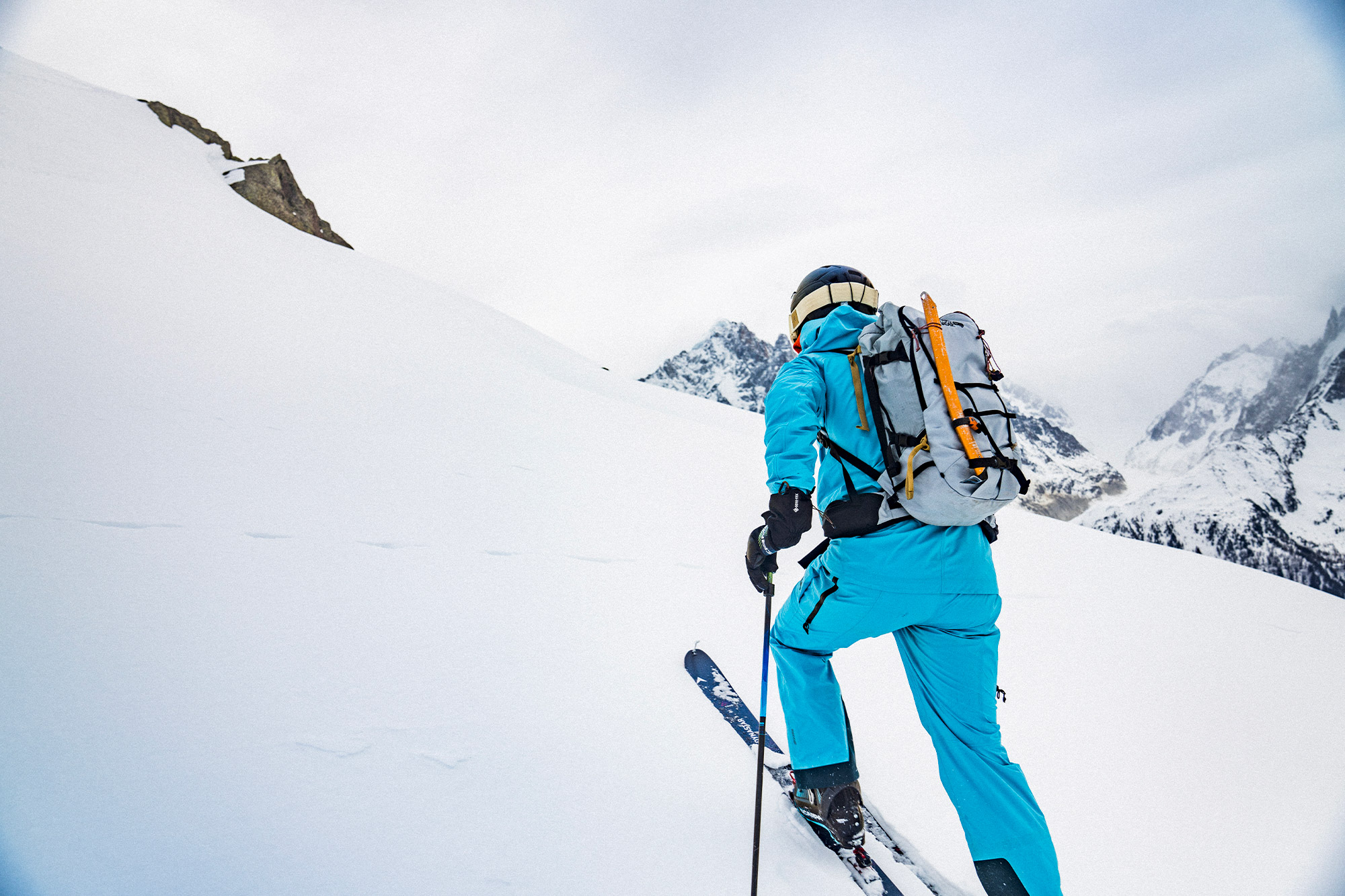 Vivian ascends a gentle snowy slope with skis and a pack