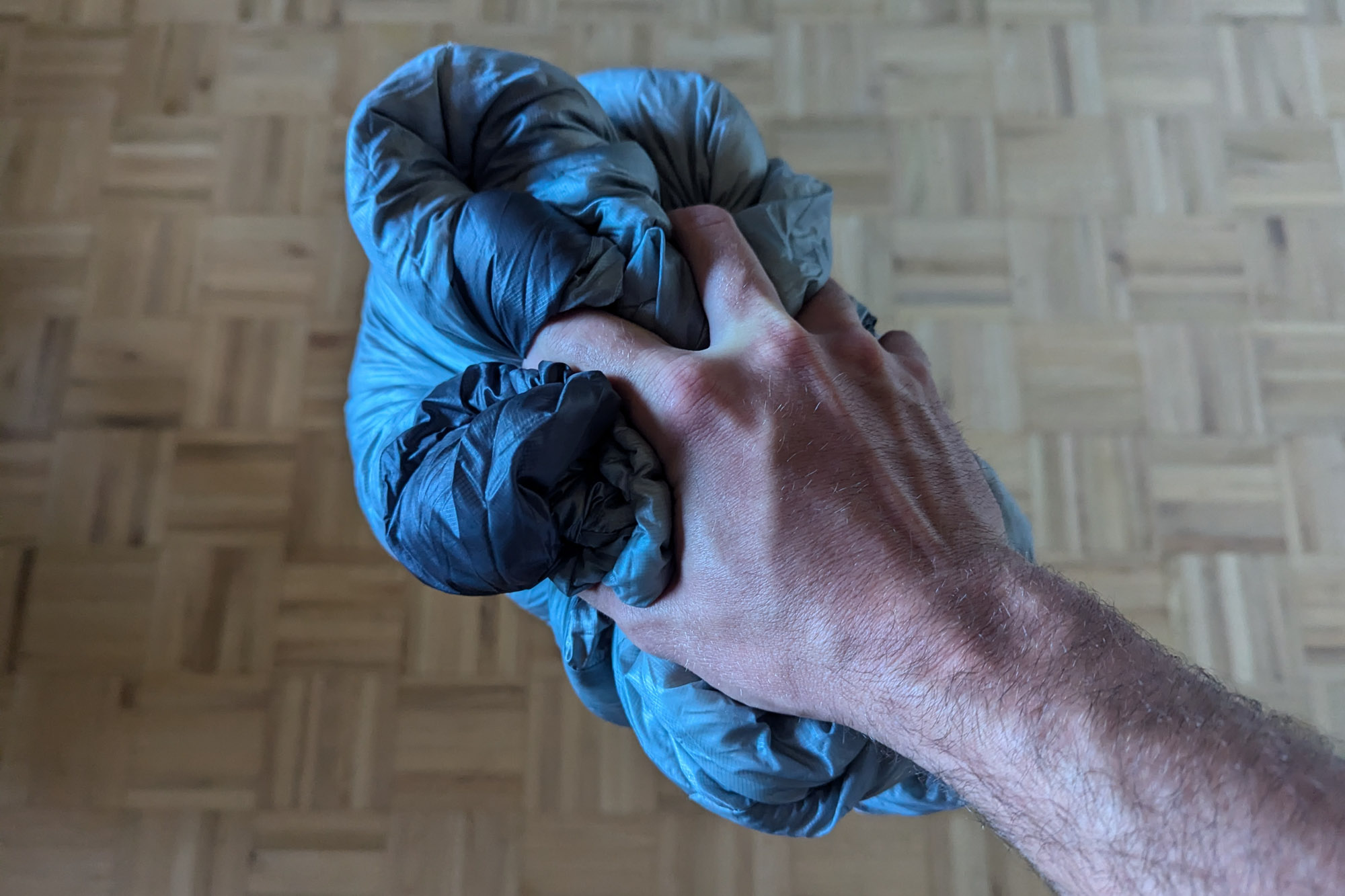 the author compresses the mythic ultra sleeping bag in his hand, showing how compact it can get