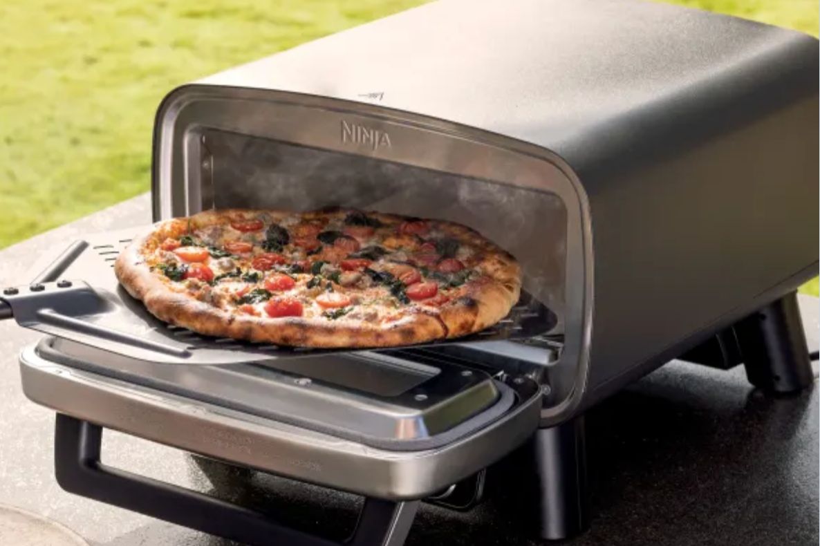 Ninja Pizza Oven with cooked pizza coming out of oven