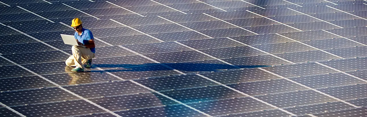 Image of a engineer with a laptop at a photovoltaic farm.