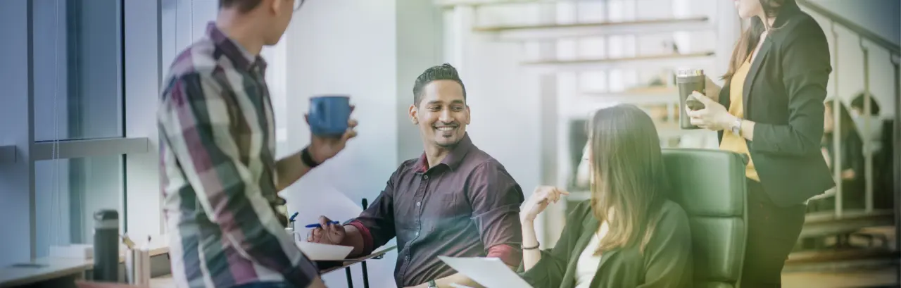Male employee in wheelchair having cheerful discussion with colleague in an office workstation