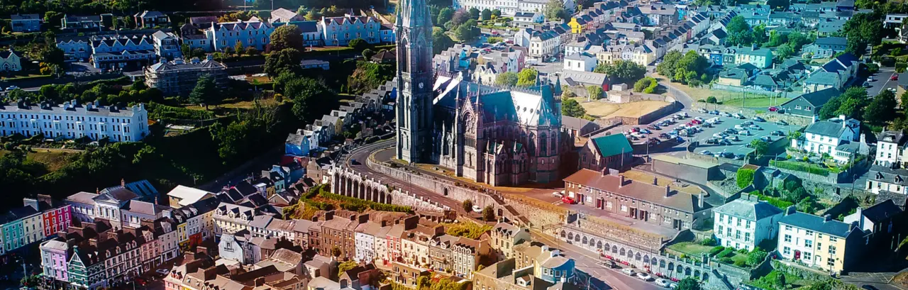 An Aerial View of Cobh Town, with a tall church in the center surrounded buy houses