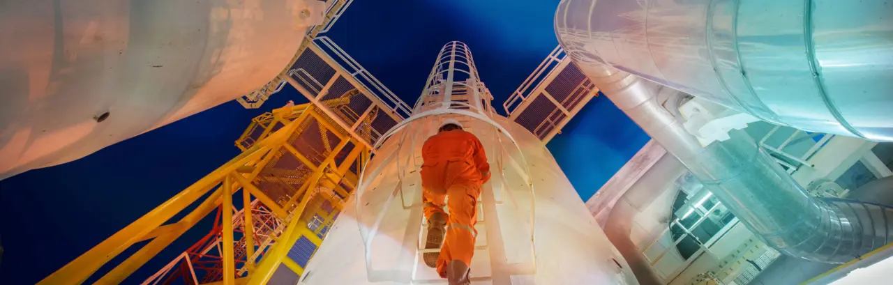 Man in coveralls climbing a ladder on a worksite