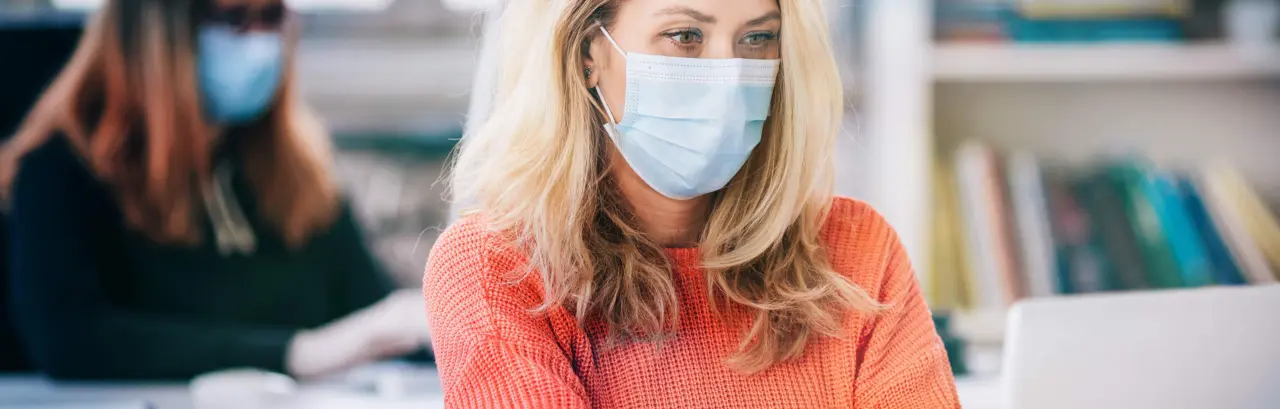 Colleagues in the office working while wearing medical face mask during COVID-19