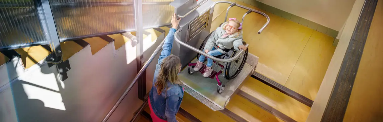 Mother with a young child living with cerebral palsy using electric wheelchair lift.