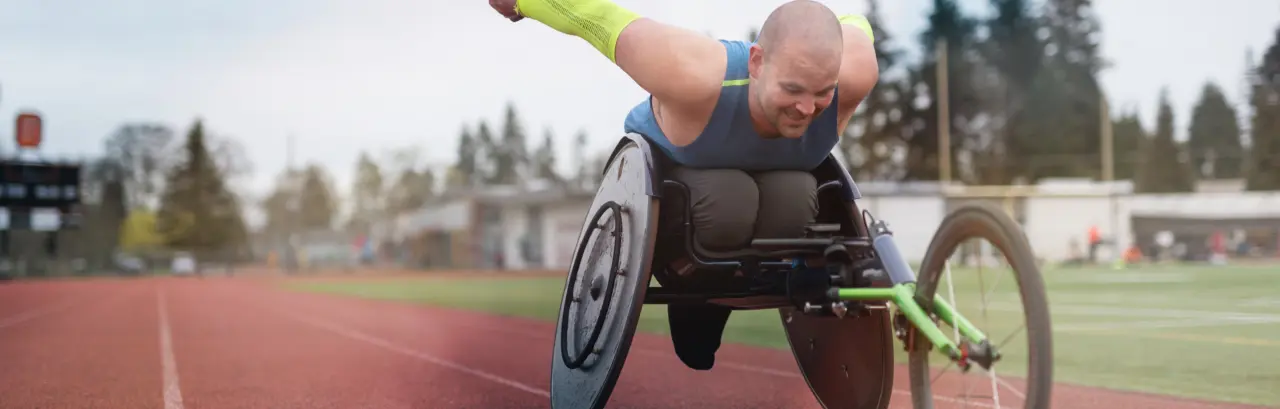 A Caucasian para athlete trains at a stadium track in his wheelchair.
