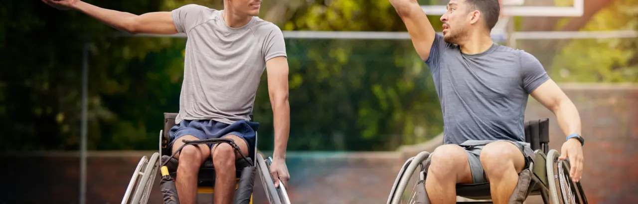 Tow young men in wheelchair playing basketball on court