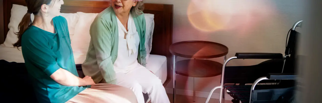 A senior woman happily chatting with her daughter on bed.