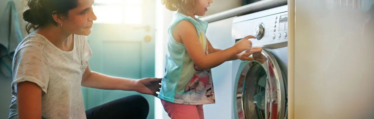 Shot of a mother and daughter using a washing machine
