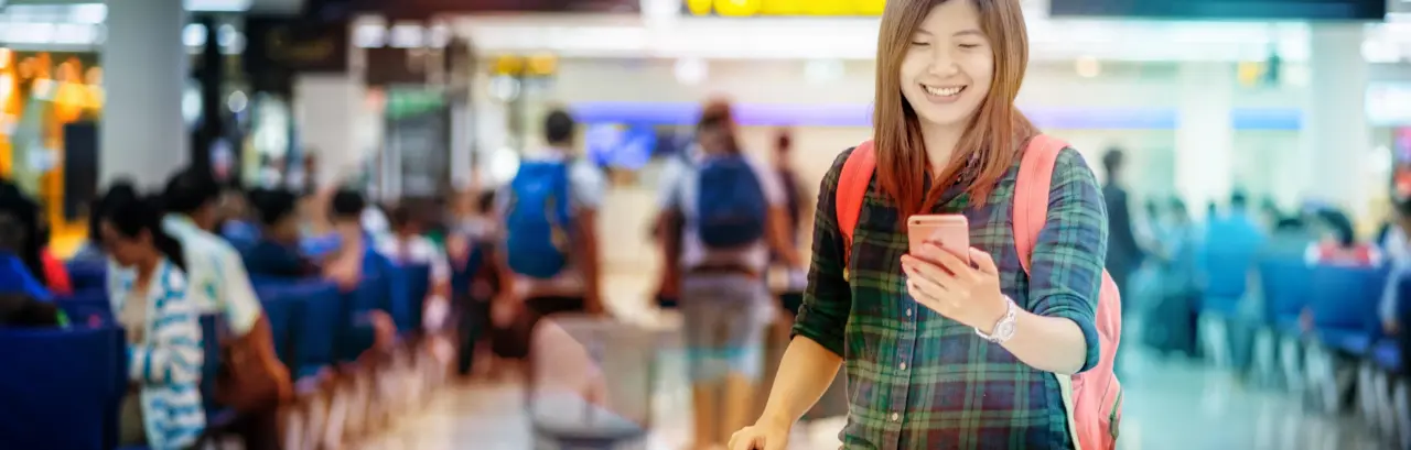 Asian traveler with luggage holding the smart mobile phone for check-in at the airport