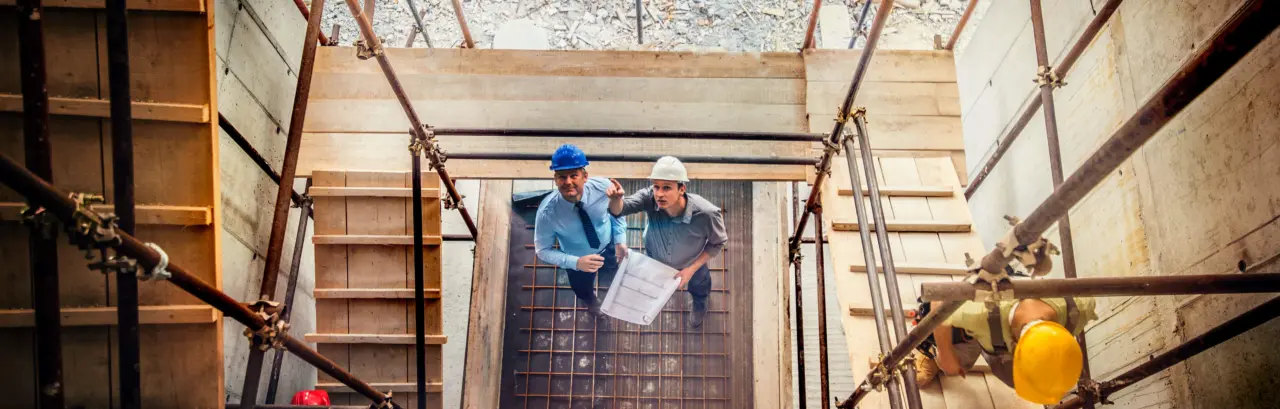 Two architects looking blueprint on a construction site
