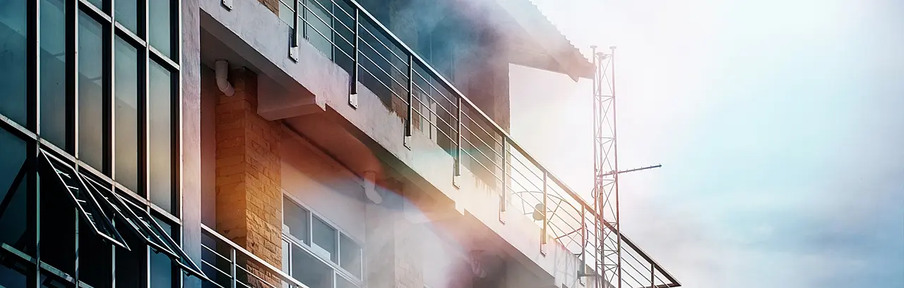 The smoke coming out of the front of the high building due to a fire.