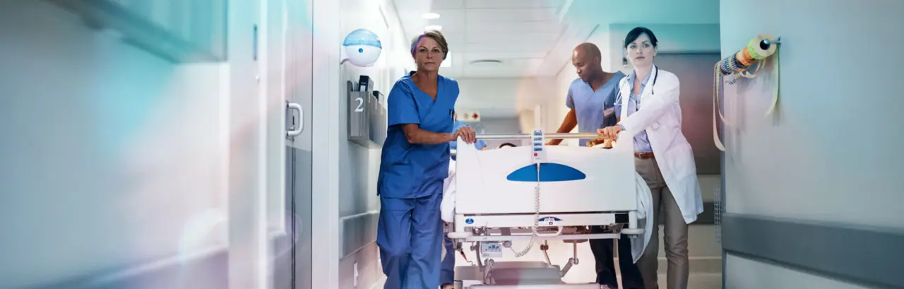 Full length shot of a medical team pushing a patient down the hallway in a gurney