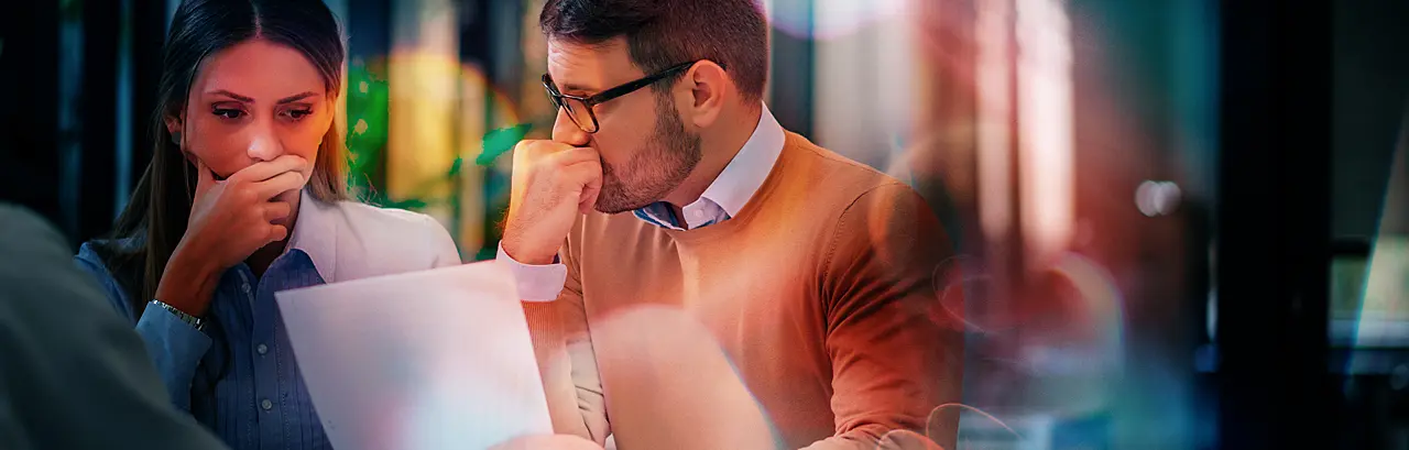 Portrait of a couple with financial problems looking at document in financial adviser's office.