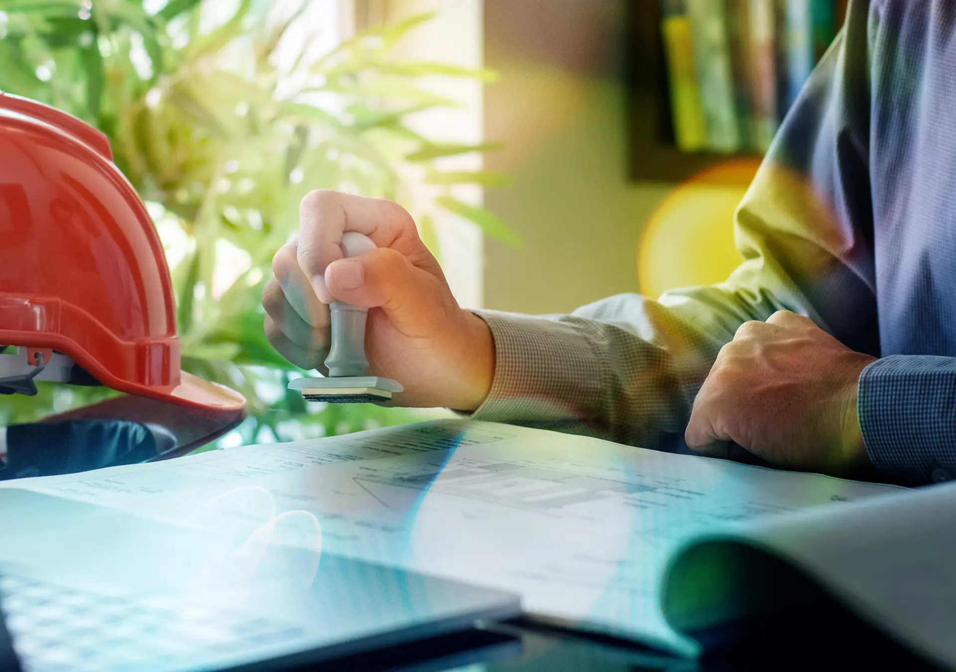 Male engineer hand stamping rubber stamper on blueprint paperwork at office. 