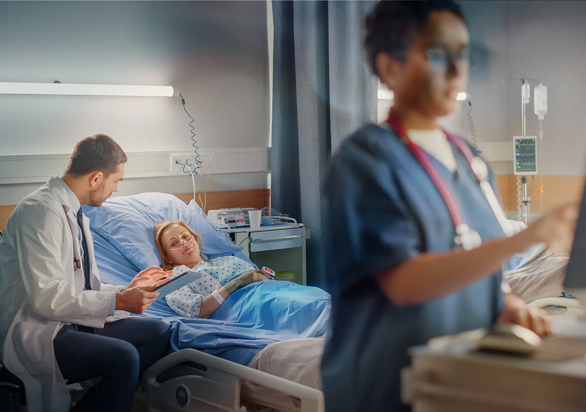 Female Head Nurse Uses Medical Computer, In the Background a Doctor is Consulting a Patient