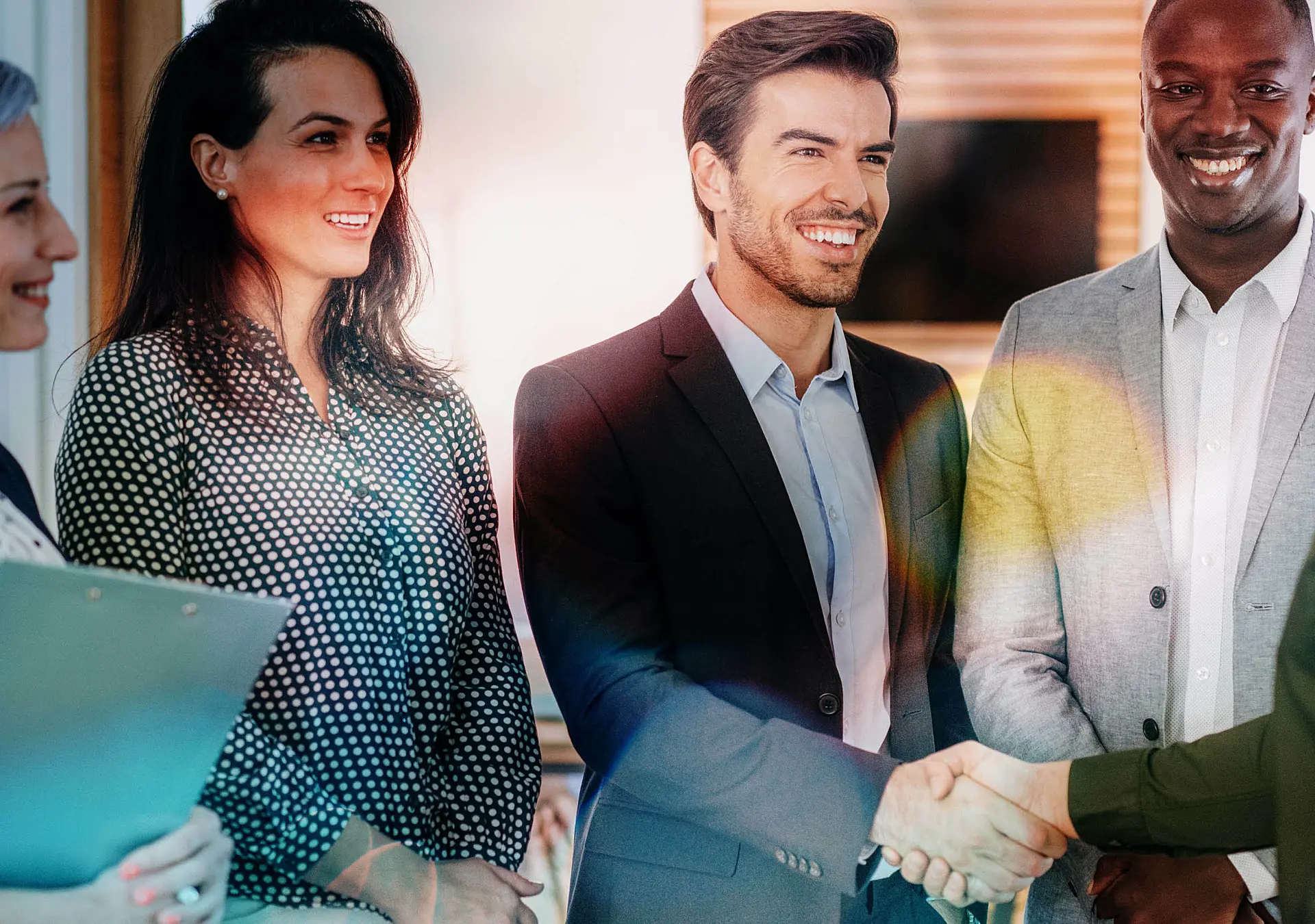 Group of business people in the office, two of them shaking hands, looking happy