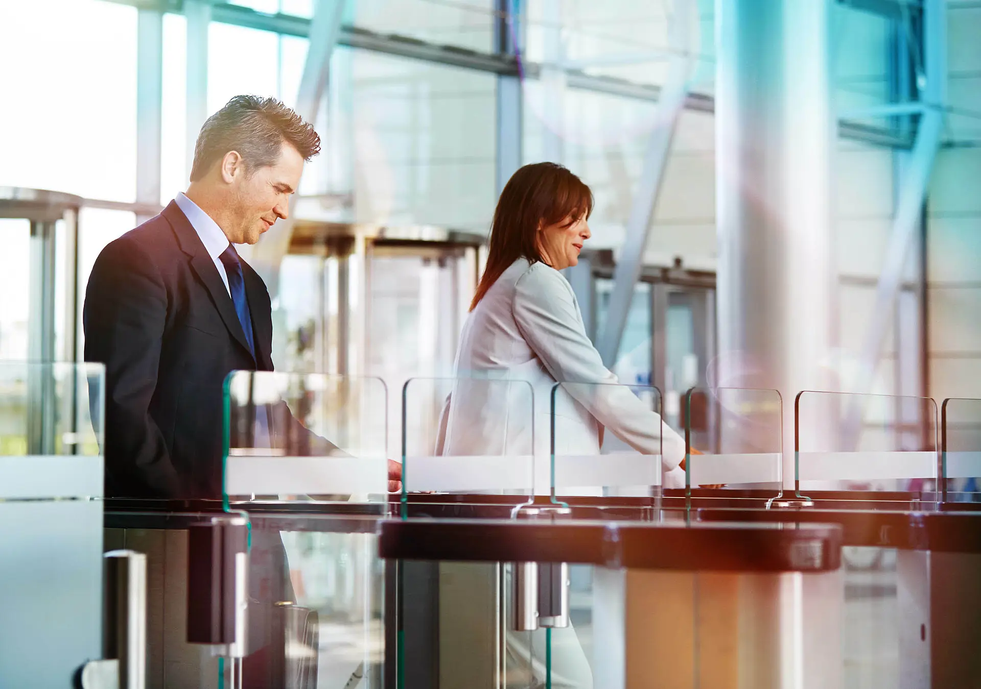 two businesspeople entering their workplace through security turnstiles