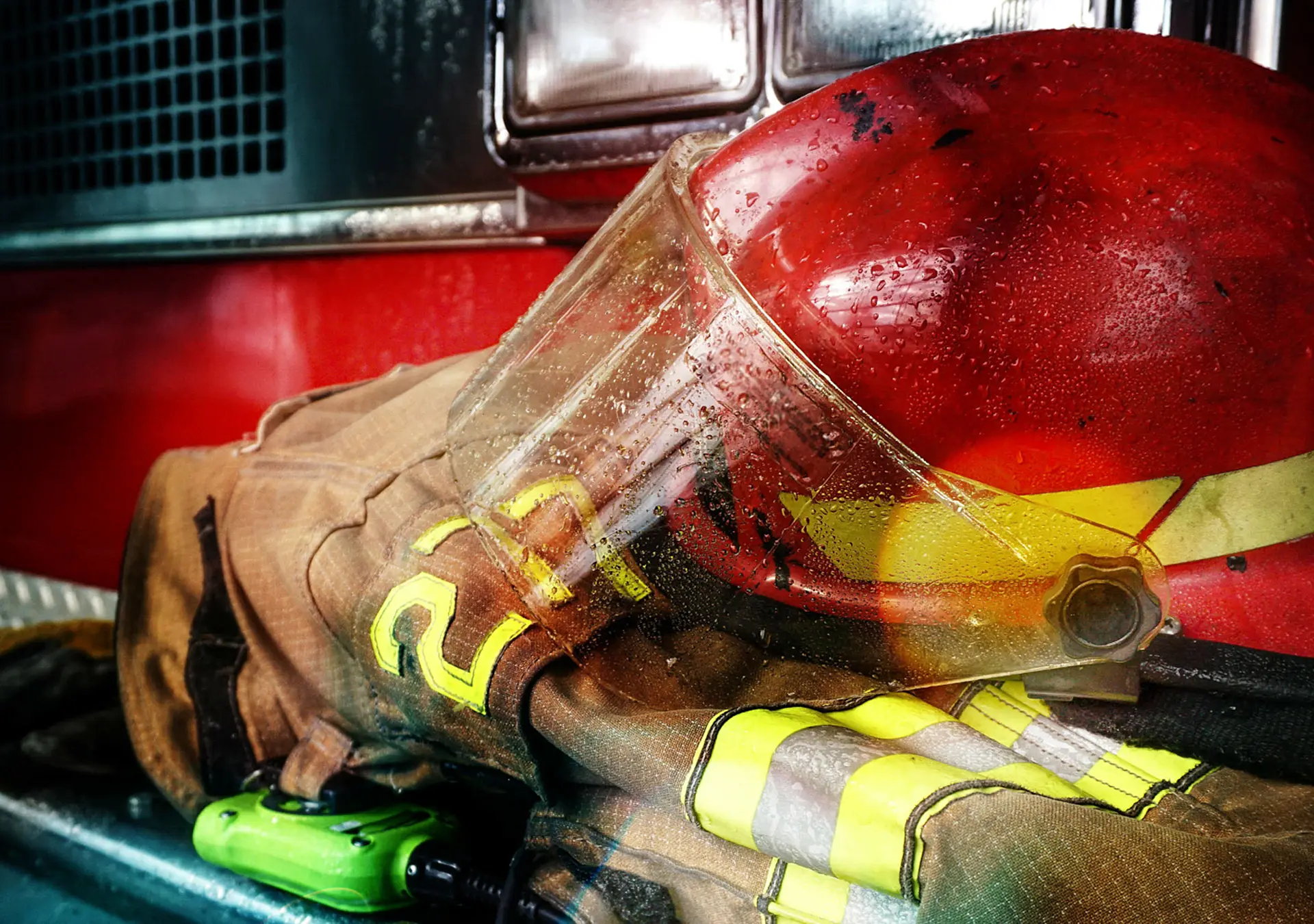 Firefighter protection gear, helmet, gloves on the bumper of the fire truck