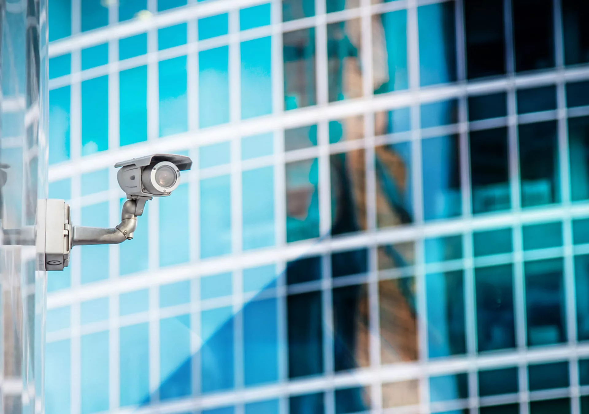 Security Camera on office building, reflecting in building behind it.