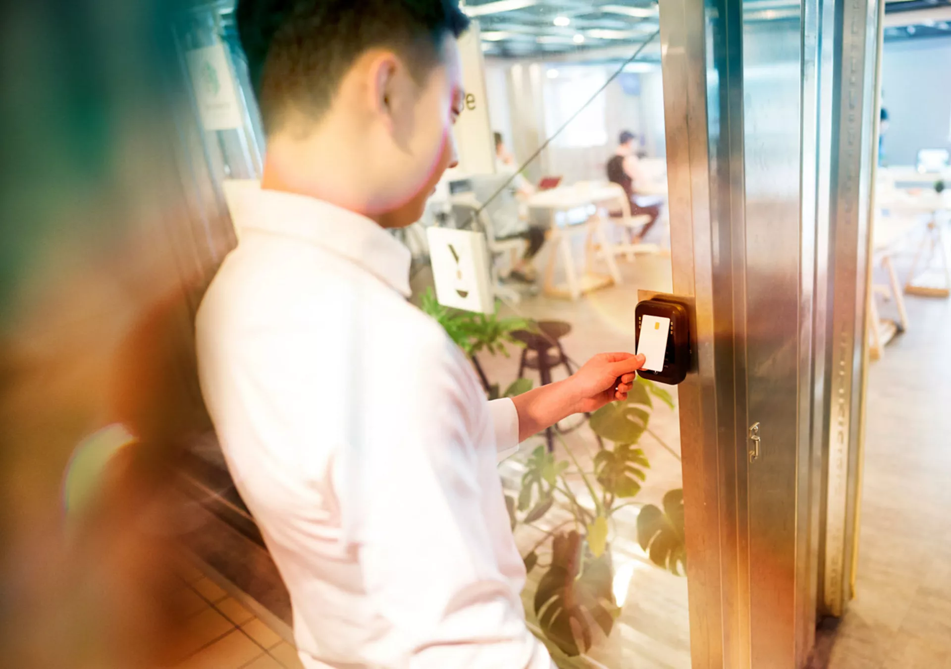 Young man unlocking door at his office with an electronic key card