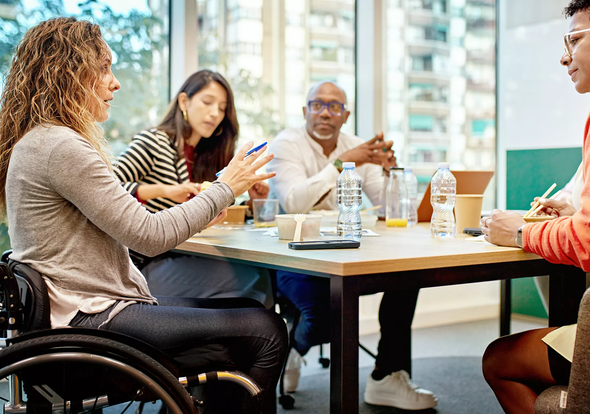 Diverse group of corporate professionals sitting around conference table conversing