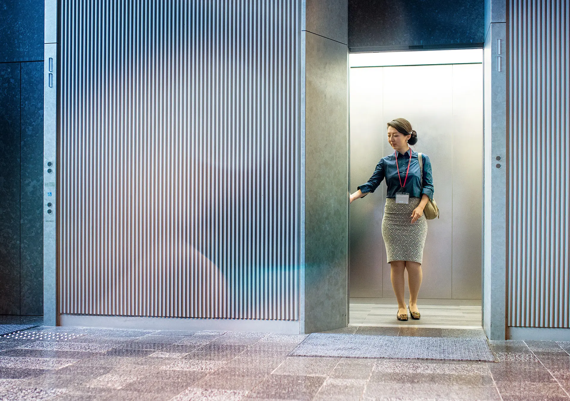 Asian businesswoman standing in elevator, waiting for doors to close.