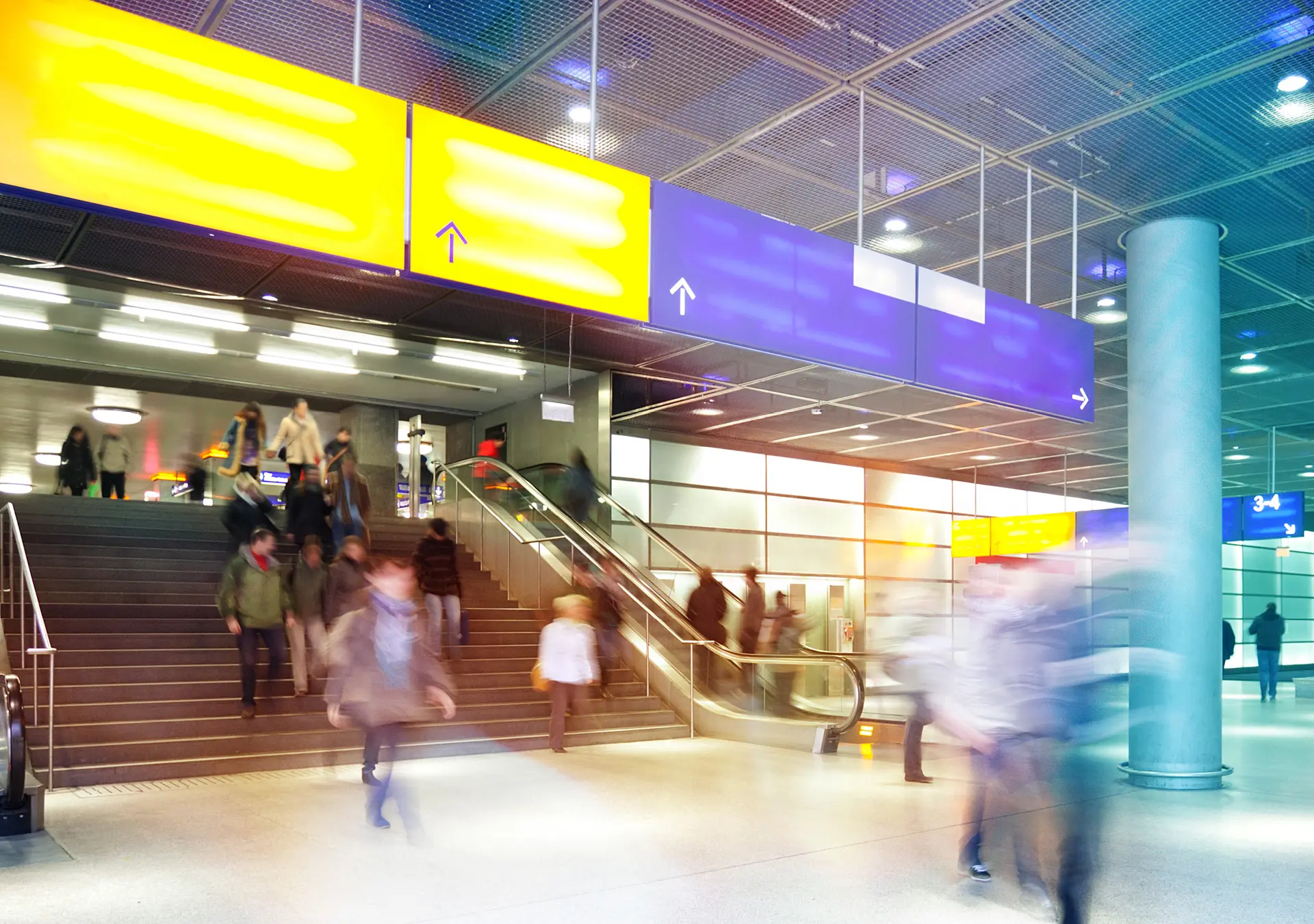 Indoor image of modern train station with commuters walking to catch trains