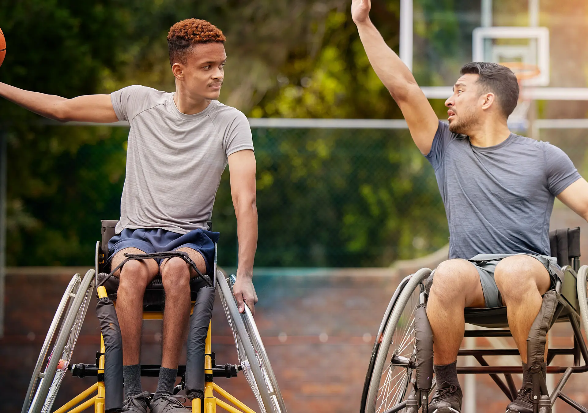 Tow young men in wheelchair playing basketball on court